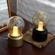 two glass globes sitting on top of a table next to each other with lights in them