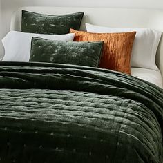 a bed with green and orange pillows on top of it