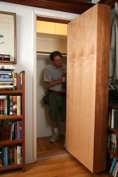 a man standing in the doorway of a room with bookshelves on either side