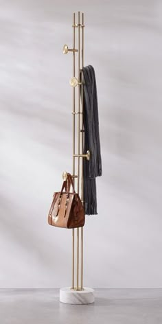 a coat rack with two purses and a scarf hanging from it's sides