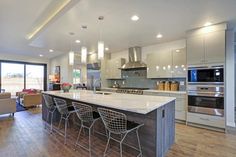 a large kitchen with an island in the middle and chairs at the counter top, along with lots of windows