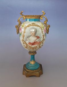 an ornate vase with a painted lady on it's side and gold trimmings