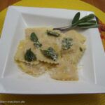 a white plate topped with ravioli and spinach