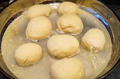 doughnuts are being cooked in a pan on the stove top with boiling water