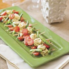 a green plate topped with skewered vegetables and veggies on top of it