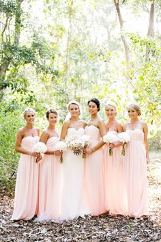 a group of women standing next to each other in front of trees and leaves on the ground