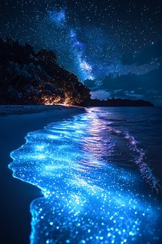 the stars shine brightly in the night sky above the ocean and beach, as seen from an island