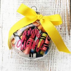 a basket filled with crayons on top of a wooden table next to a yellow ribbon