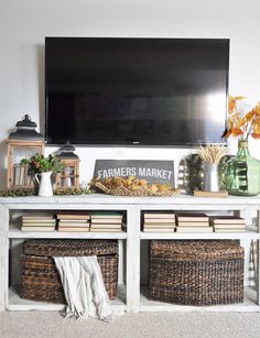 an entertainment center with baskets, books and a flat screen tv