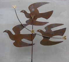 a metal sculpture with birds on it's back and two hearts in the middle