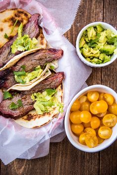 steak tacos with guacamole and cherry tomatoes on the side next to it