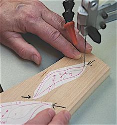 a man is using a pair of scissors to cut fabric on a piece of wood