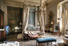 an ornate bedroom with four poster bed and chandelier hanging from the ceiling, decorated in blue and gold