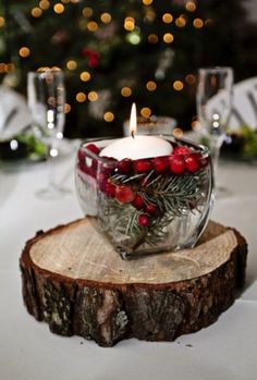 a glass bowl filled with red berries sitting on top of a wooden slice