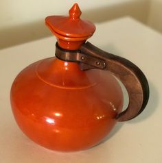 an orange tea pot with a metal handle