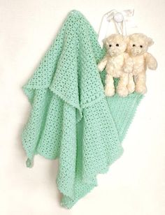 two teddy bears are sitting next to a green crocheted towel and a white stuffed animal