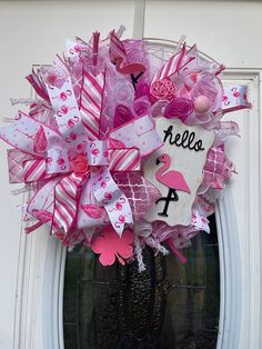 a pink and white wreath is hanging on the front door to welcome someone with her name