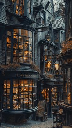 an old - fashioned book store is lit up at night in the middle of a cobblestone street