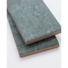 two pieces of slate sitting side by side on top of each other in front of a white background