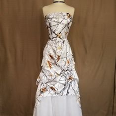 a dress on a mannequin with white and brown designs in the front, as well as black and gold accents