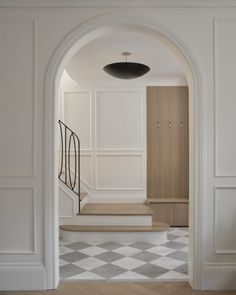 an open doorway leading to a hallway with white walls and checkered tile flooring