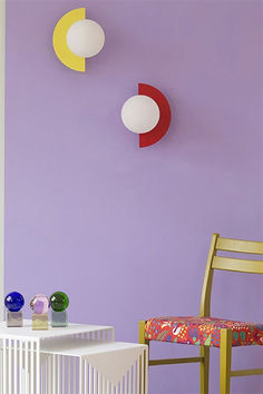 a chair and table in front of a purple wall with three circles hanging on it