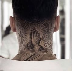 the back of a man's head with tattoos on his neck and hands behind him