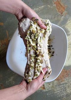 a person holding something in their hand on top of a white plate with food all over it