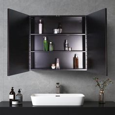 a bathroom sink sitting under a mirror next to a shelf filled with bottles and soaps