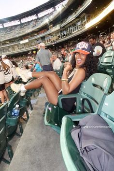 a woman sitting in the bleachers at a baseball game with her legs crossed