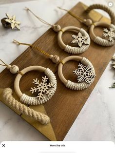 wooden hoop earrings with snowflakes hanging from them on a wood board next to christmas decorations