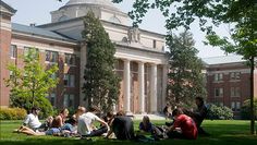 people sitting on the grass in front of a building