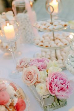 a table topped with lots of desserts and flowers on top of it's tables