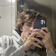 a man taking a selfie with his cell phone in front of him and wearing a hoodie