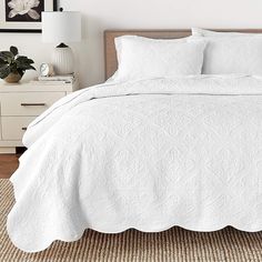 a bed with white bedspread and pillows on top of it in a bedroom