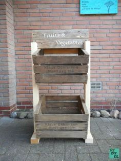 a wooden crate sitting on the side of a brick building next to a sign that says fruits & vegetables