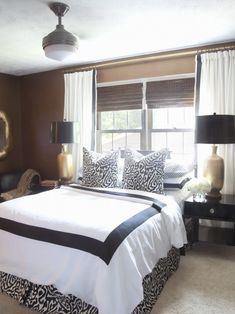 a bedroom with brown walls and white bedding, two lamps on either side of the bed