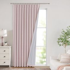 a living room with a white couch and pink curtains in front of a large window