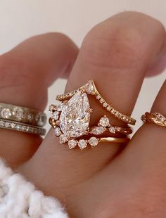 a woman's hand with three different rings on it and one has a pear shaped diamond