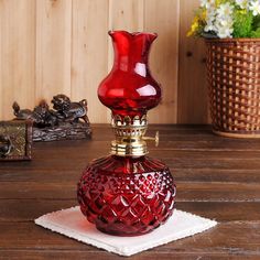 a red vase sitting on top of a wooden table