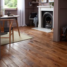 a living room filled with furniture and a fire place next to a table on top of a hard wood floor