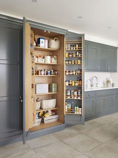 an open pantry in the middle of a kitchen with gray cabinets and white counter tops