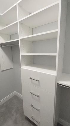 an empty closet with white shelves and drawers