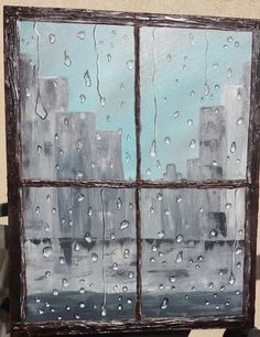 a window with rain drops on it in front of a cityscape and blue sky