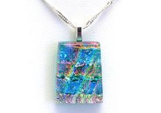 a square glass pendant is hanging on a silver chain with a colorful pattern in the center