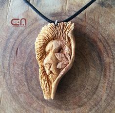 an animal's head carved into a wooden piece on a leather cord necklace with a black cord