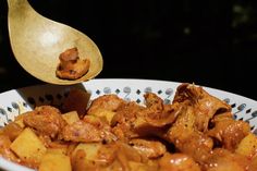 a wooden spoon scooping some food out of a white bowl on top of a table