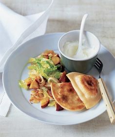 a white plate topped with food next to a bowl of yogurt and a fork