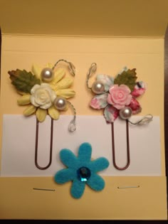 two paper clips with flowers and pearls on them