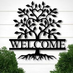 a metal sign that says welcome with a tree on it